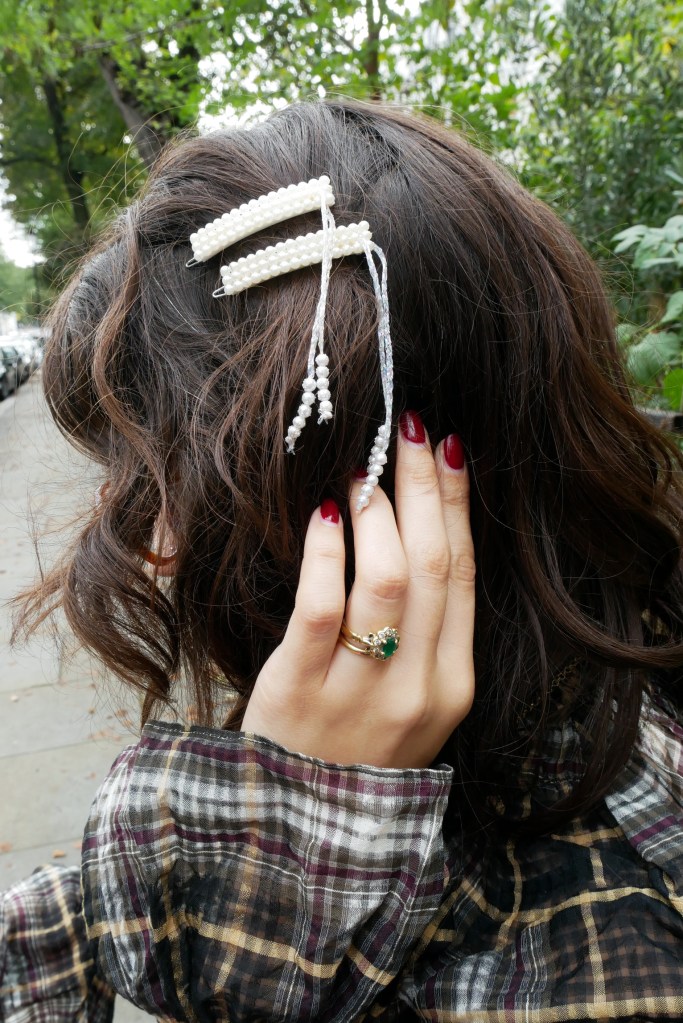 Close up on Katie's hair with two faux pearl hair clips each with a dangling sparkly sting holding a few more faux pearls.